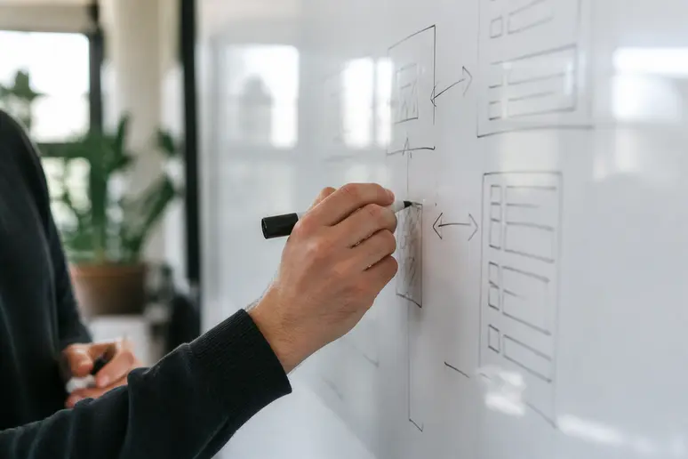 Hands writing data extraction parameters and keyword recovery metrics on a planning whiteboard