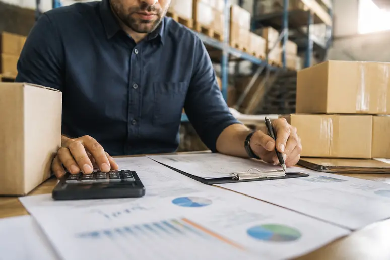 Logistics manager calculating gross profit margins and shipping threshold costs on spreadsheets