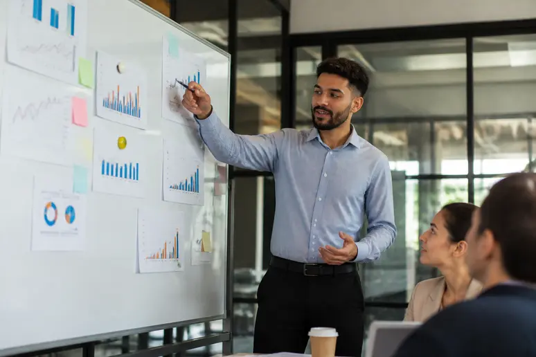 Marketing analyst reviewing return on investment metrics on a collaborative strategy whiteboard